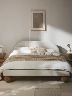 Cama tapizada con patas esféricas de madera Rena